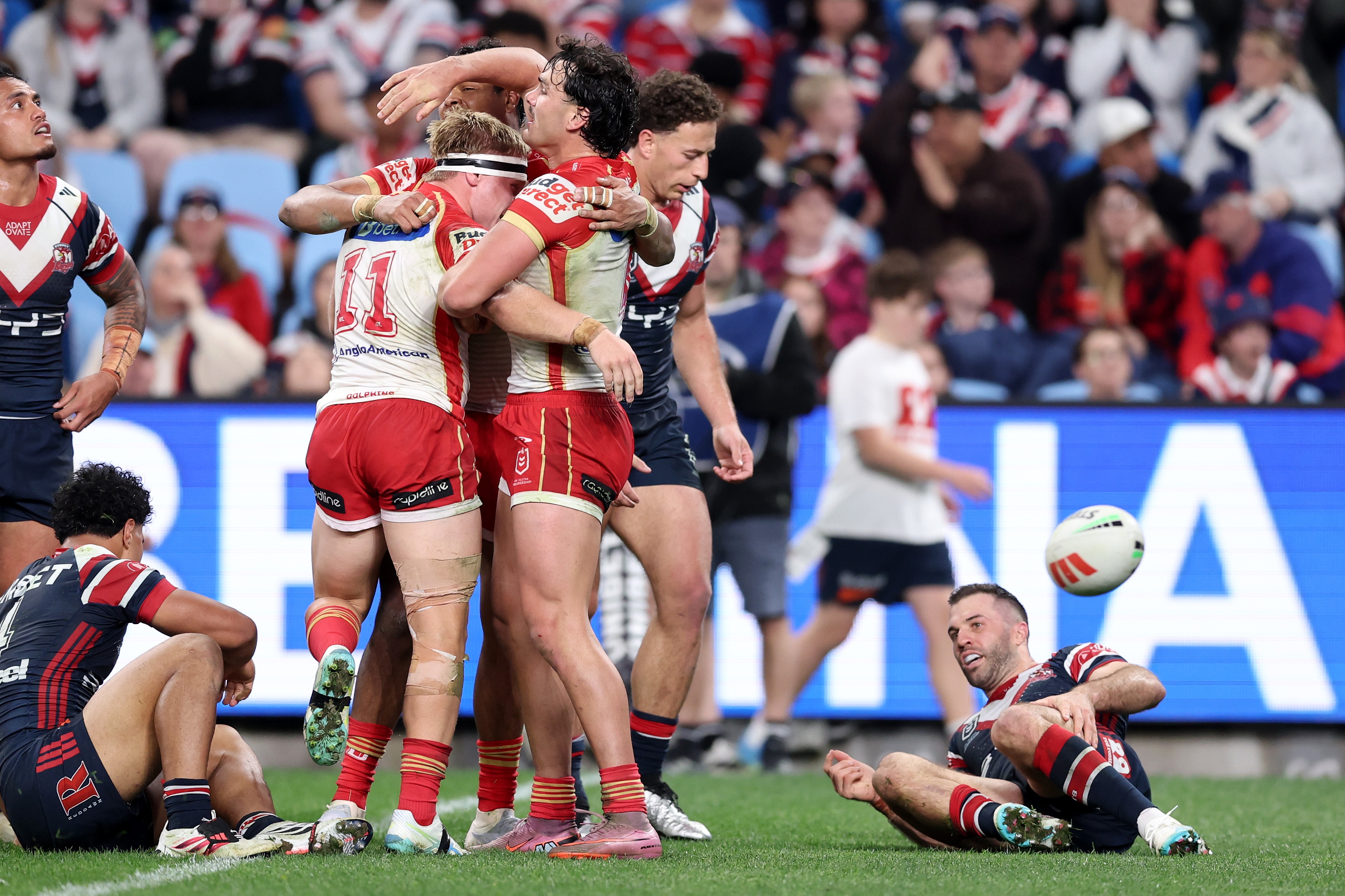 Rugby league players in red and white celebrate a try