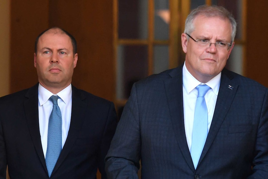 Scott Morrison and Josh Frydenberg walk down a hallway to deliver a press conference about the JobKeeper payment.