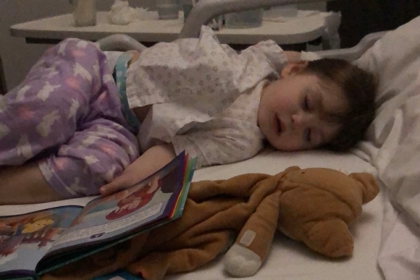A toddler asleep in a hospital bed