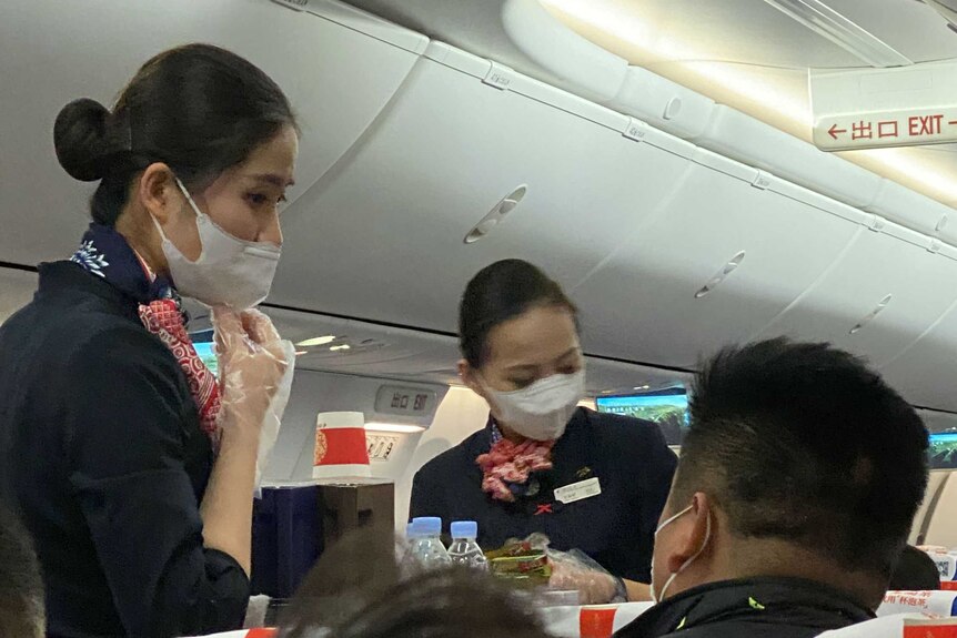 Flight attendants wearing masks inside plane.