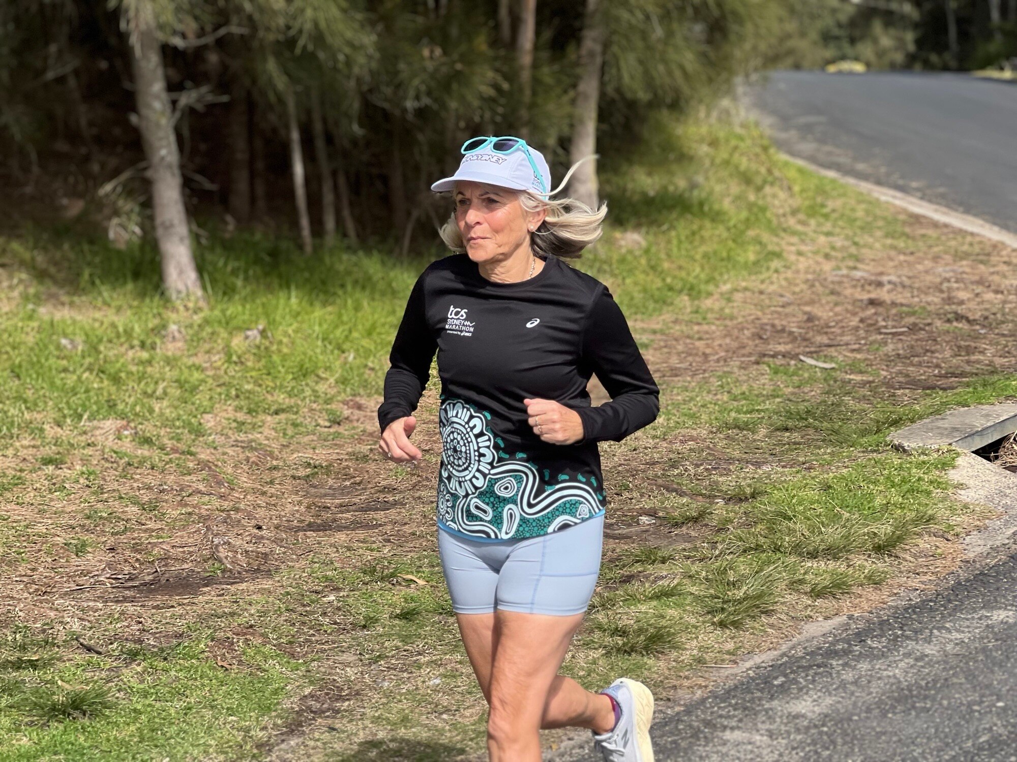 A blonde woman is seen running ahead of a marathon event
