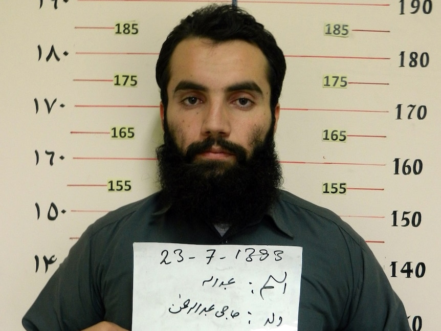 Taliban prisoner Anas Haqqani in a prison holding up a sign.