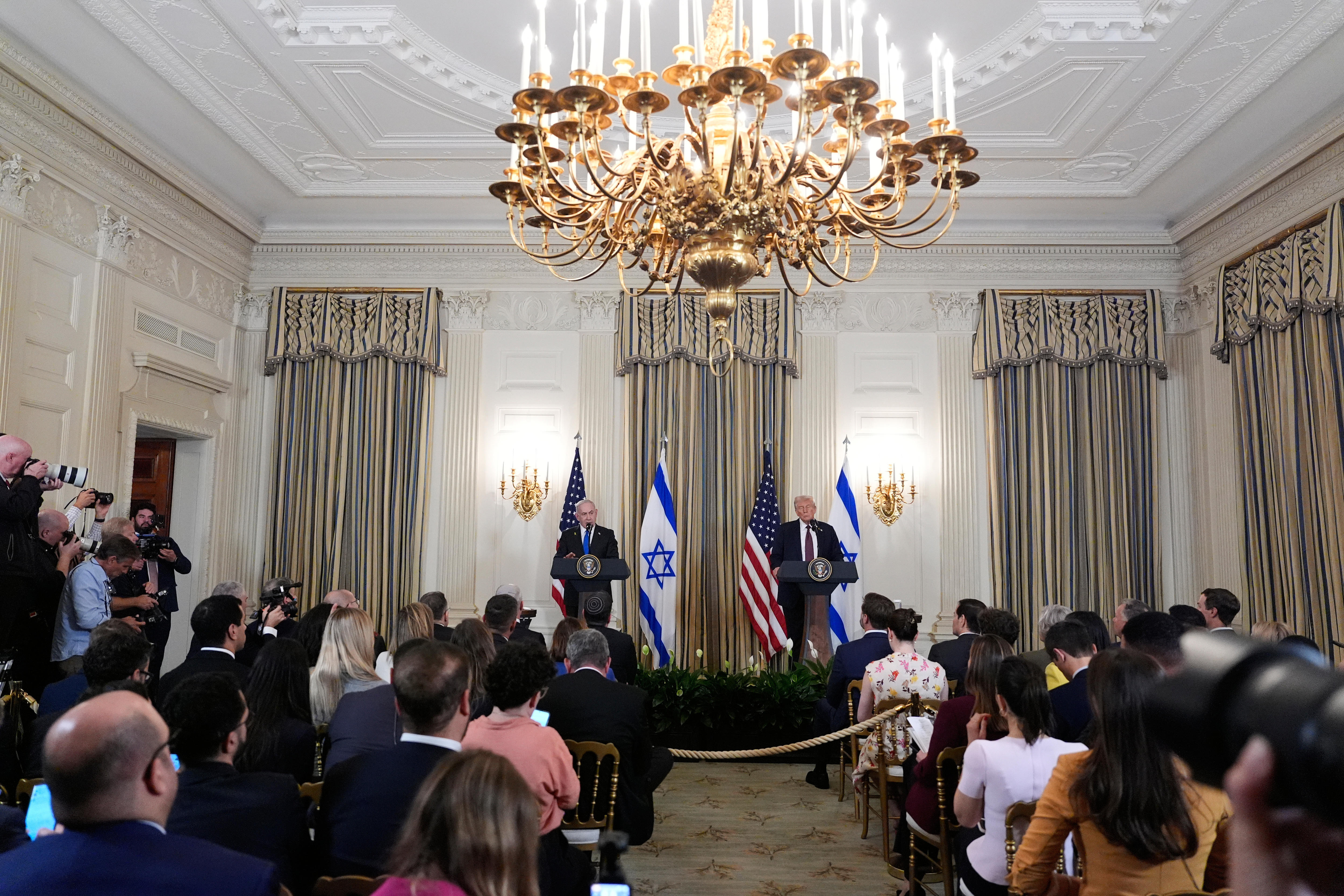A grand room with people in chair facing a stage .