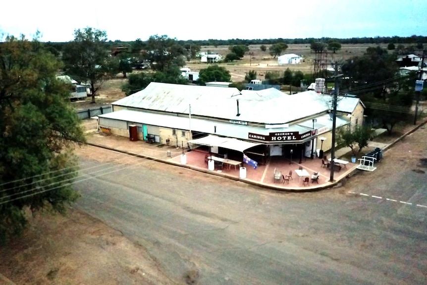 A faded hotel is viewed from above in a small country town.
