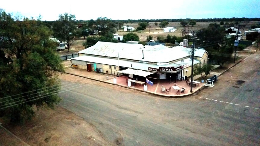 A faded hotel is viewed from above in a small country town.