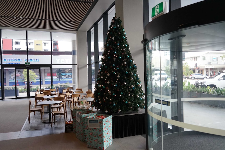 A Christmas tree inside an office lobby space with cars and a streetscape outside.