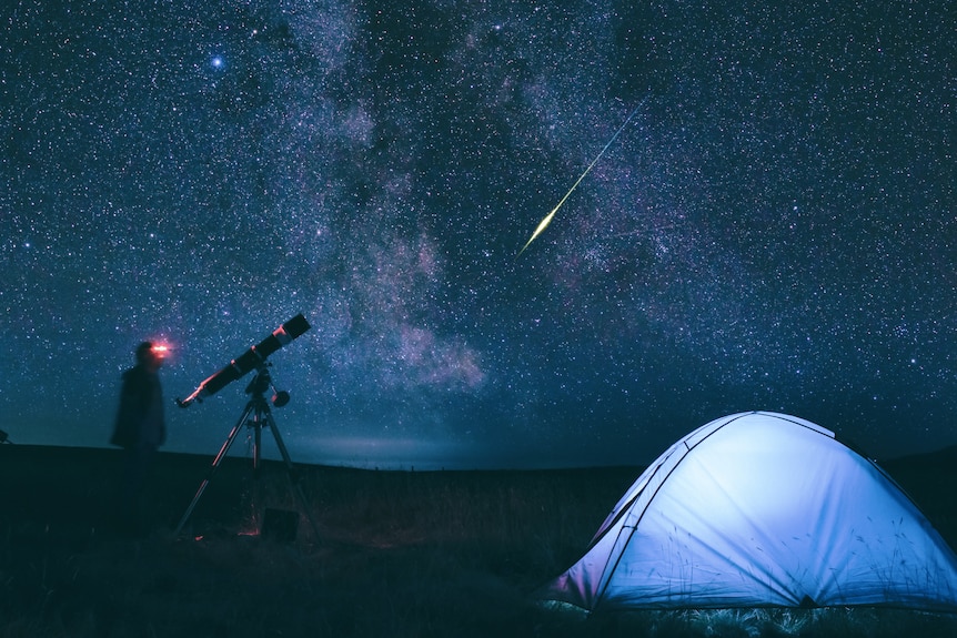 astronomers at night with meteor in background