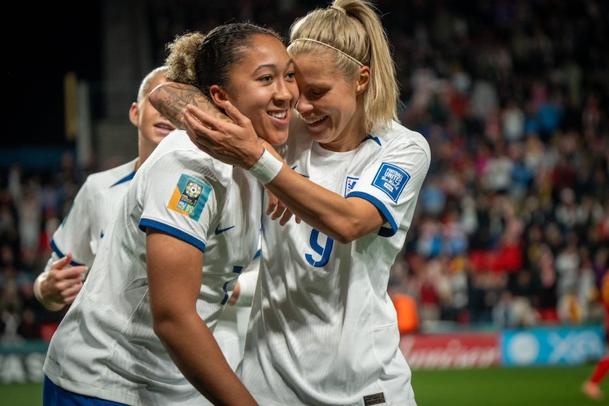 An England goalscorer gets a hug from her teammates during a Women's World Cup game.