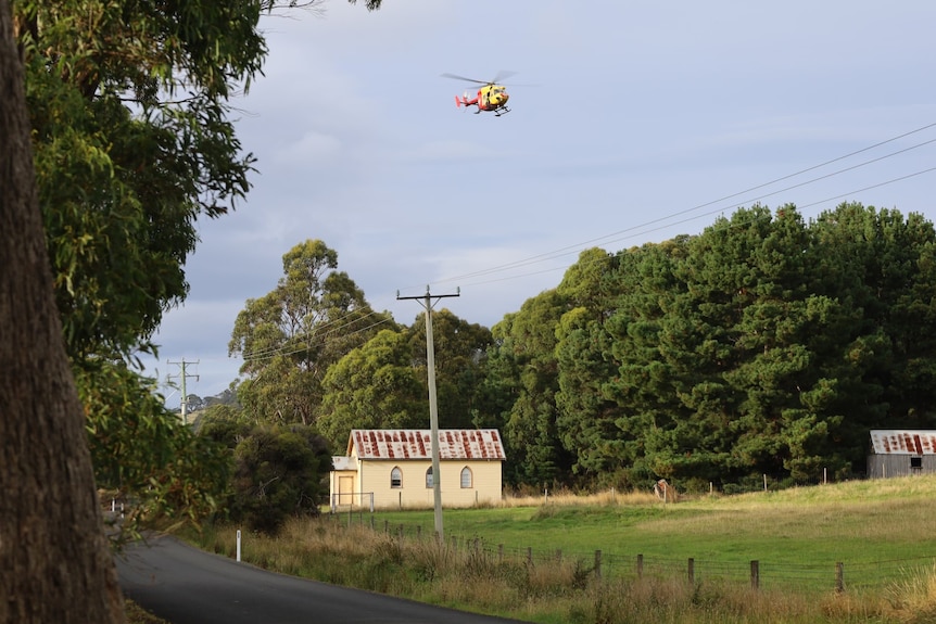 A helicopter over a rural property and road.