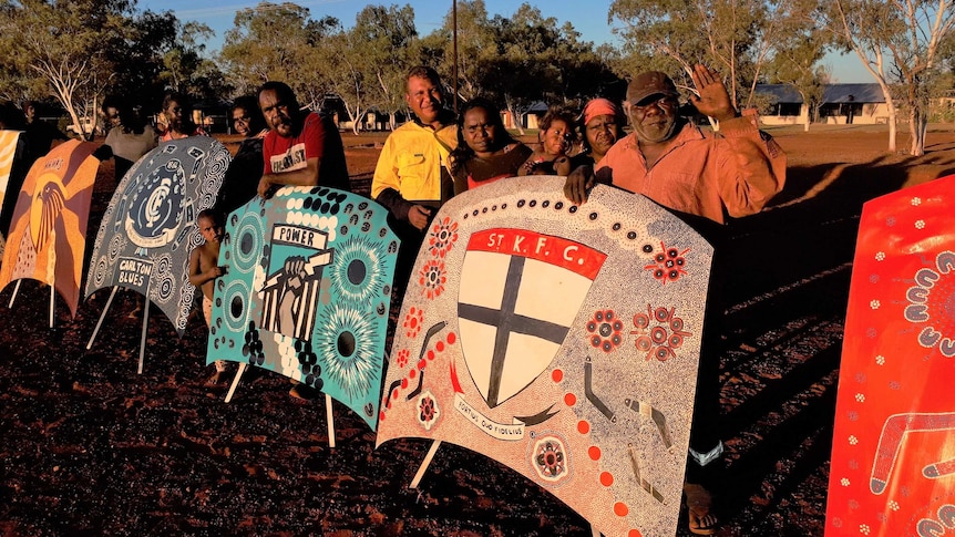 Group of Indigenous residents standing with bonnet art