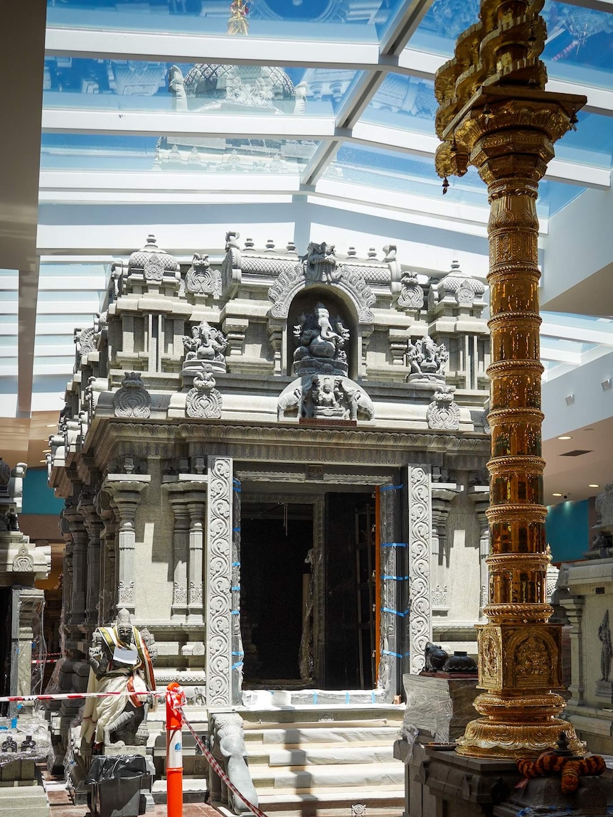 A decorative Hindu granite shrine sits inside a temple