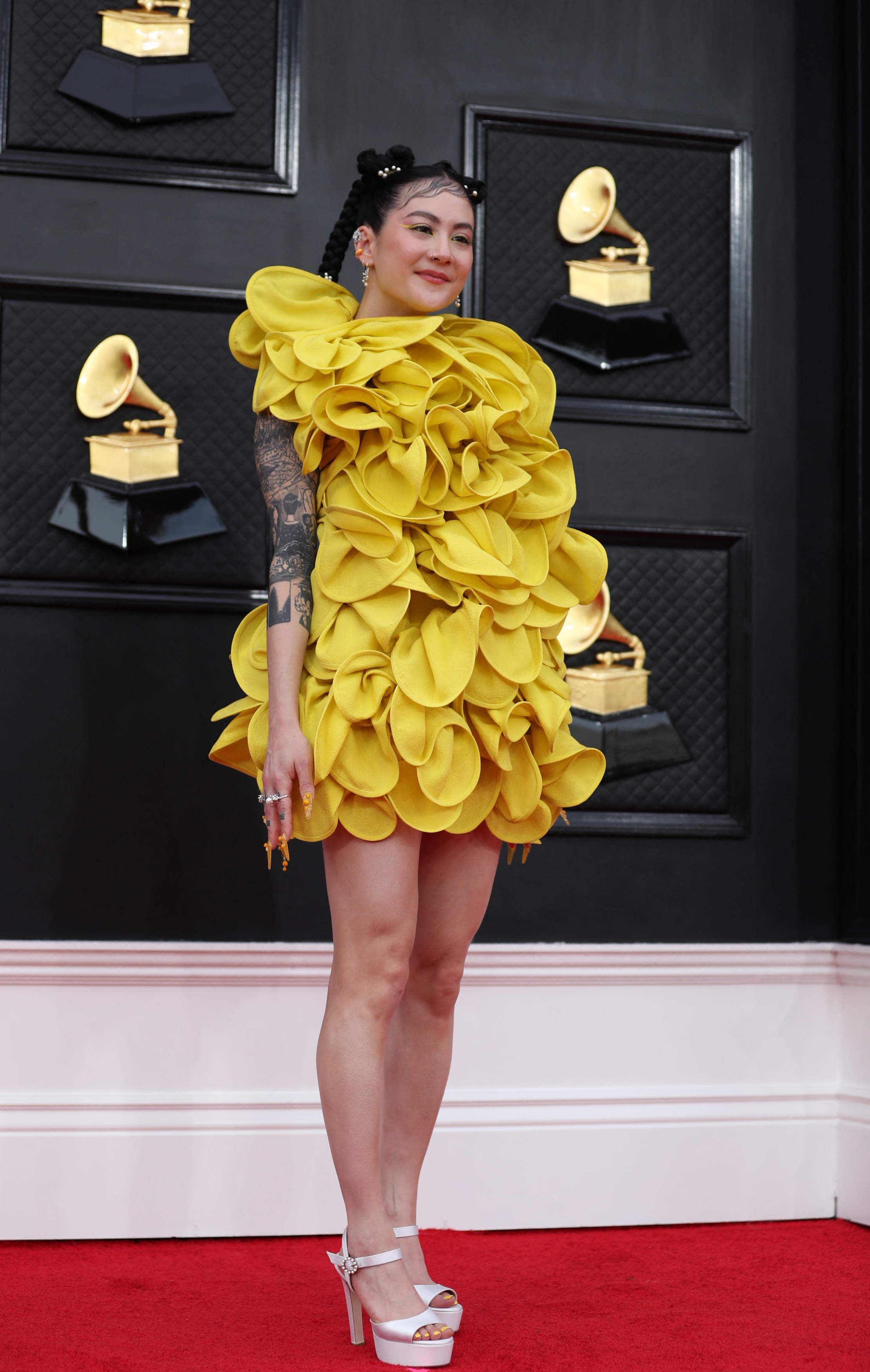 artist japanese breakfast poses on the red carpet wearing a bright yellow short dress with ruffled fabric like petals