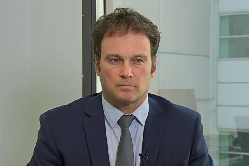 Man in a blue suit sits for an interview in a high rise office building