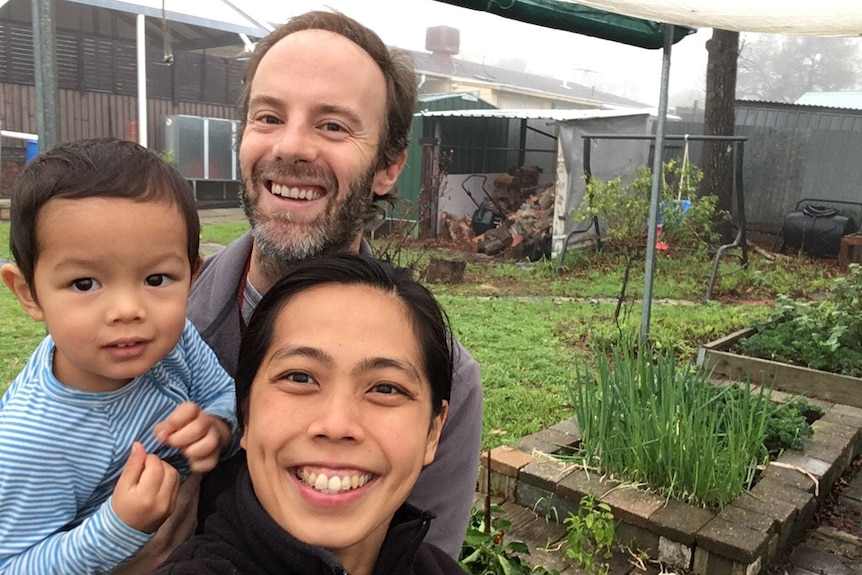 A male and female couple and a toddler doing selfie in their garden.