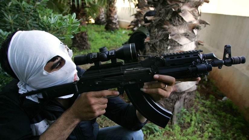 A masked militant of the Shiite Amal opposition group holds a position