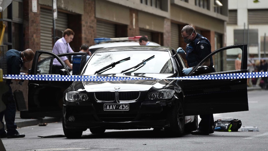 Police investigators dust a black BMW for fingerprints