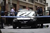 Police investigators dust a black BMW for fingerprints