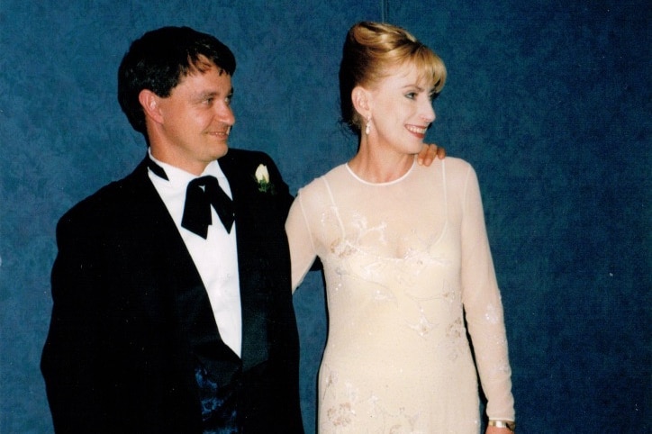 Dr Desley Lodwick and her husband John posing for a photo next to the cake on their wedding day