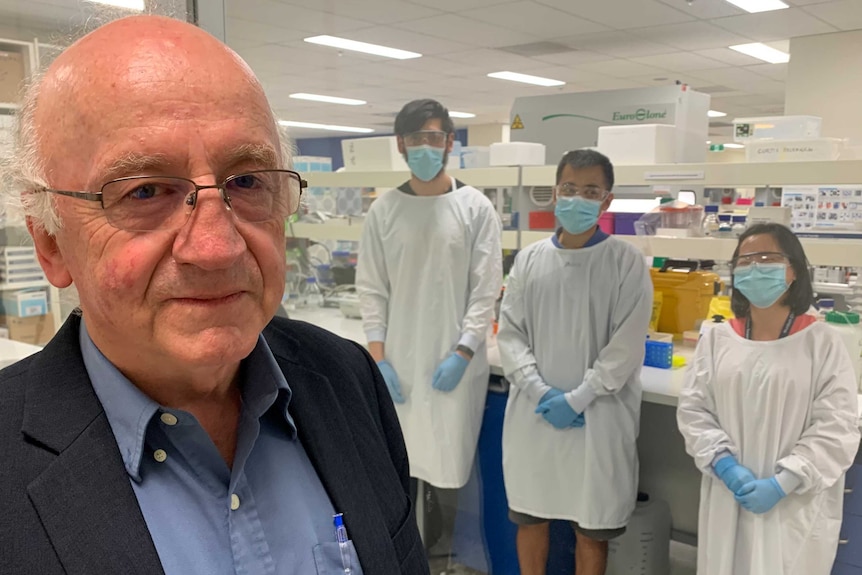 A man with grey hair stands in a lab.