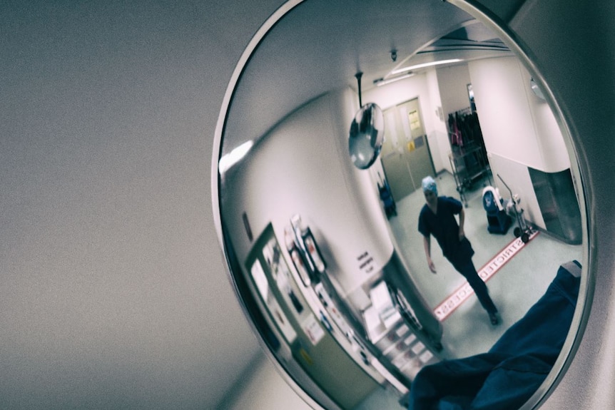 Unidentifiable hospital staff member in the reflection of a mirror