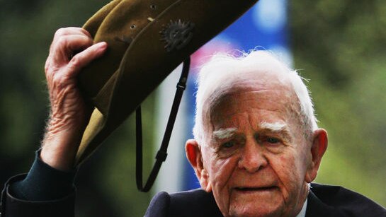 A war veteran lifts his hat to the crowd during the Anzac Day march in Sydney.