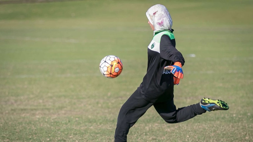 A Balga Soccer Club goalkeeper wearing a hijab punts the ball.