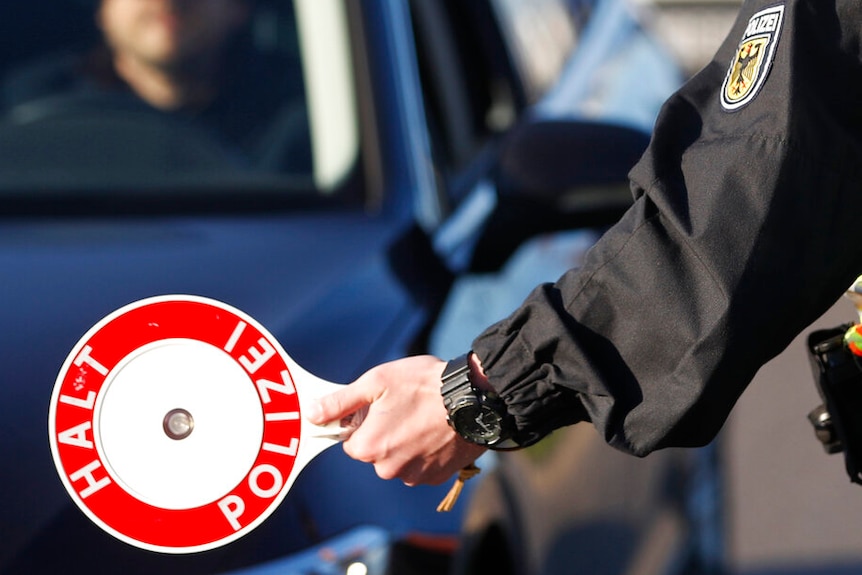 A German police officer checks vehicles at the German-France border in Kehl, Germany