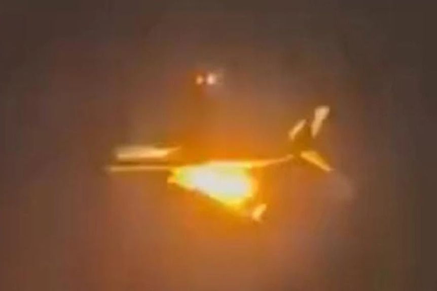 A blurry photo of a plane with a flame coming from it.