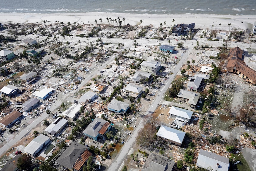 Aerial view of damaged home and debris along coastline after Hurricane Ian.