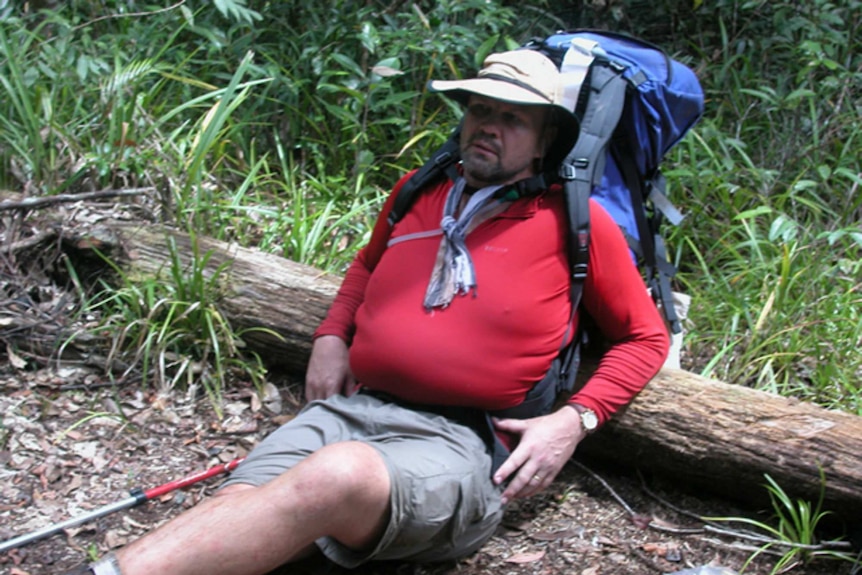 Peter FitzSimons lays against a log during the Kokoda Trail walk in 2002.