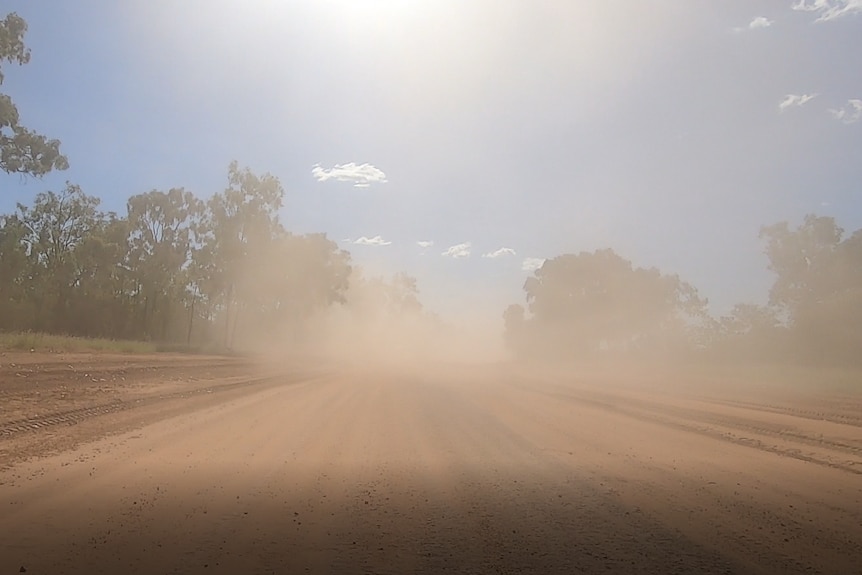 a dirt road is dusty after a truck passed