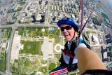 A woman in a helmet skydiving over a city.