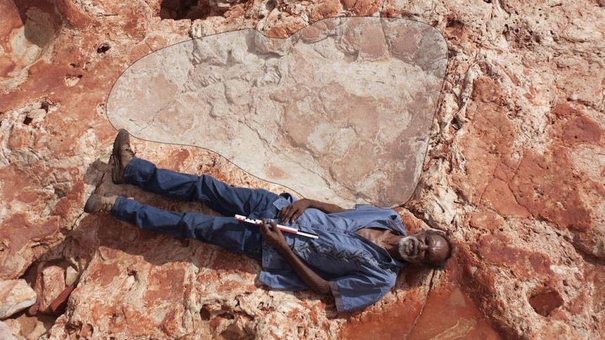 Richard Hunter lies next to the world's biggest dinosaur footprint