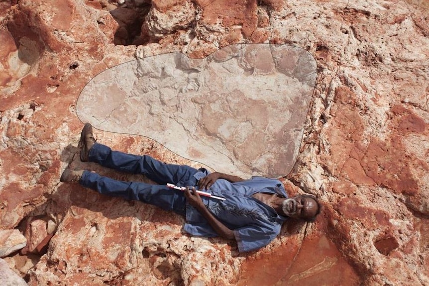 Richard Hunter lies next to the world's biggest dinosaur footprint