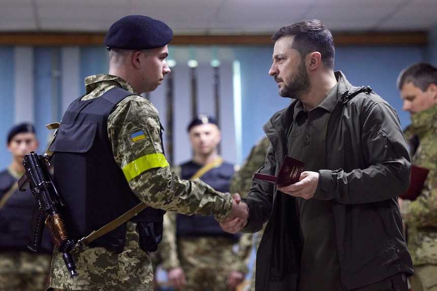 乌克兰总统泽连斯基在访问饱受战争蹂躏的哈尔科夫地区时为一名女士兵颁奖。