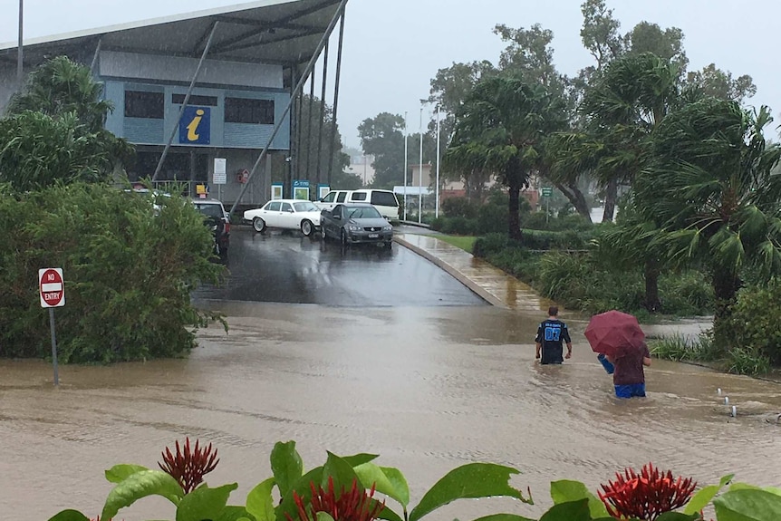 Two men wade into waters above the knee in a street at Information centre in Ingham