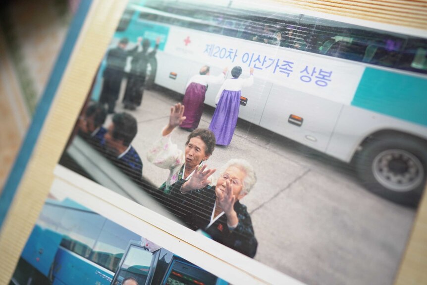 Two women wave tearfully from outside a bus window.