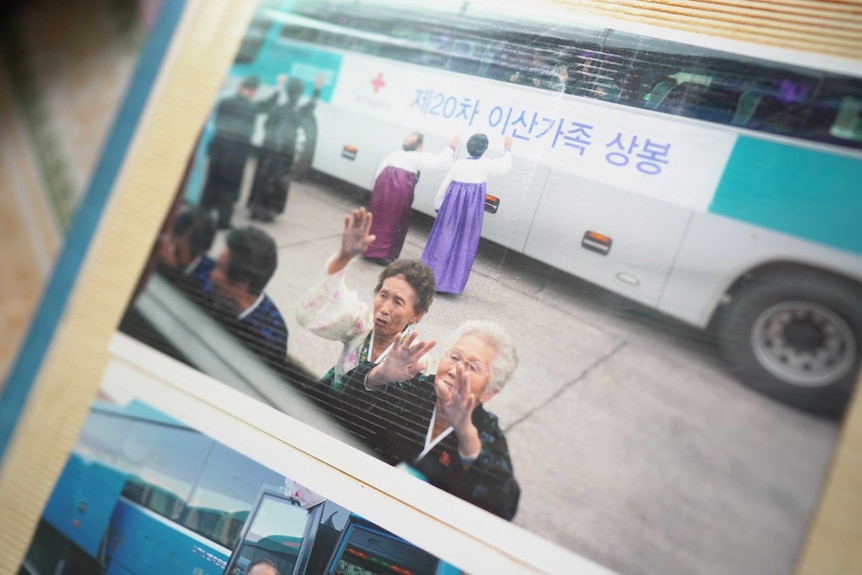 Two women wave tearfully from outside a bus window.