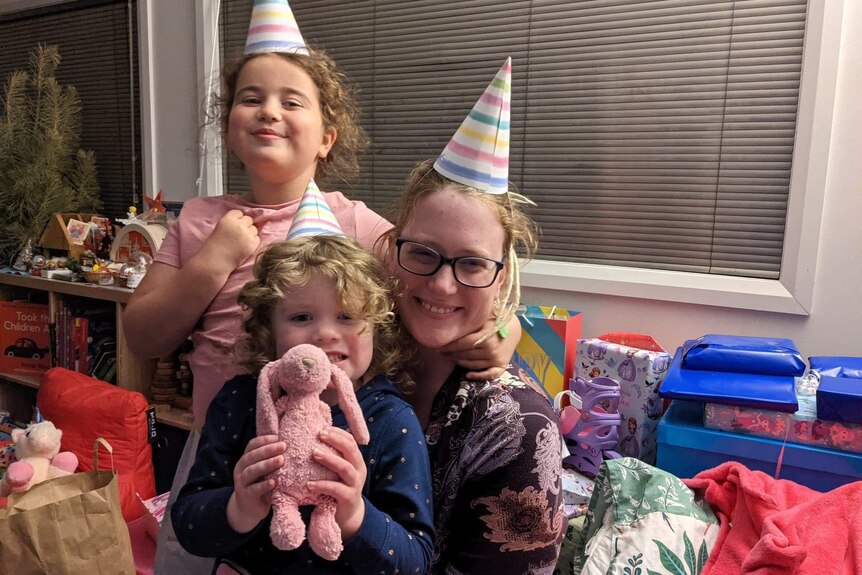 Women and two kids in party hars surrounded by presents 