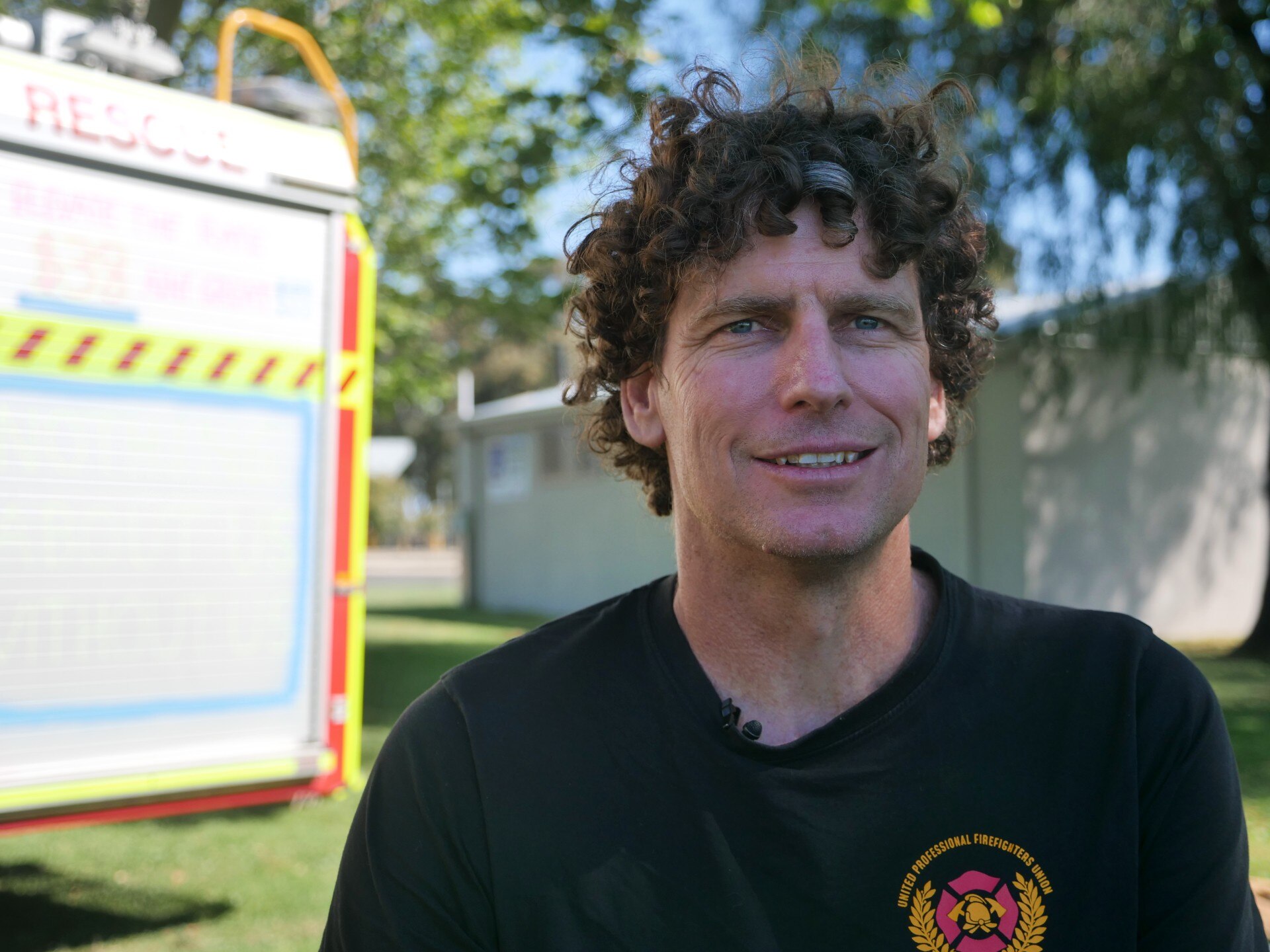 Un hombre está sentado frente a un camión de bomberos.