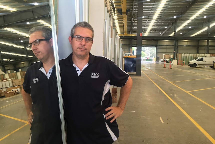 Stefan Styles standing next to a mirror in the warehouse of of Civic Shower Screens and Wardrobes in Brisbane