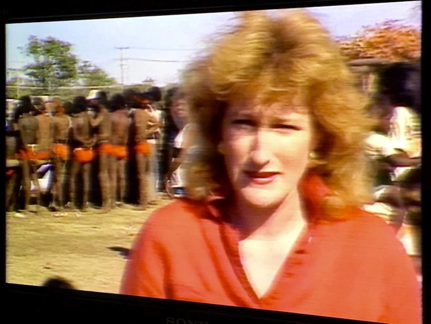 O'Neill standing in front of group of Indigenous people with backs to camera.