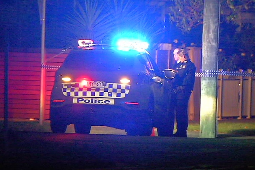 A police car with lights flashing and two police officers.