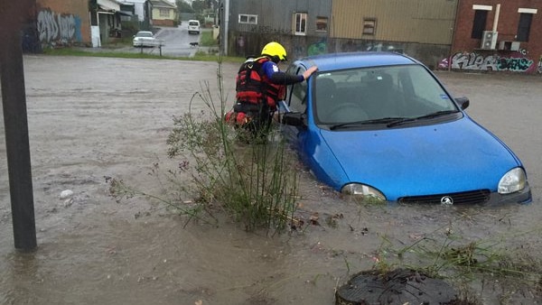A firefighter looks into a car in waist-deep floodwaters in Wallsend.