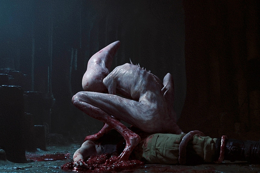 A pale creature with spikes coming out of its back hovers over a bloody body.
