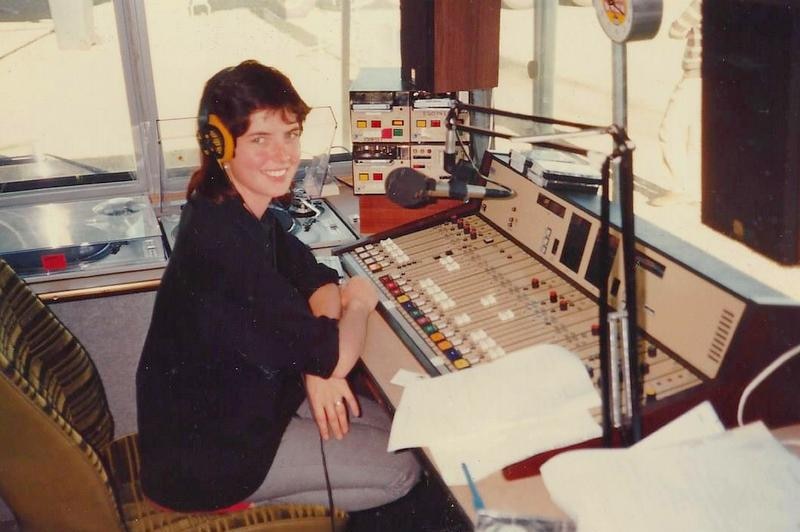 Maher wearing headphones sitting in front of microphone and old audio panel.