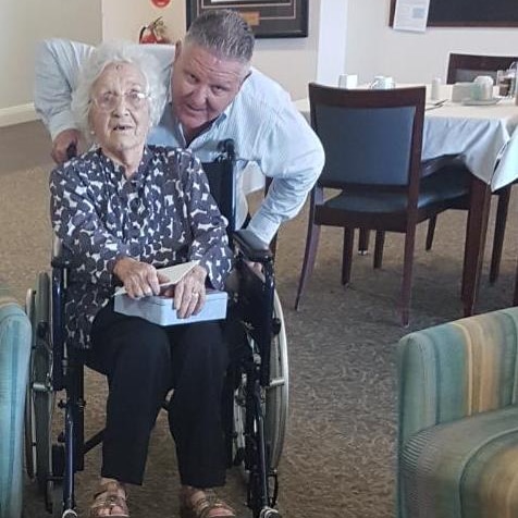 Laurietta Prentice sits in a wheelchair with her son James leaning down beside her