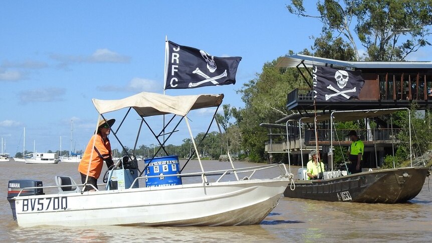 Members of the Jolly Rogers Fishing Club sail along the Fitzroy River in Rockhampton looking for rubbish