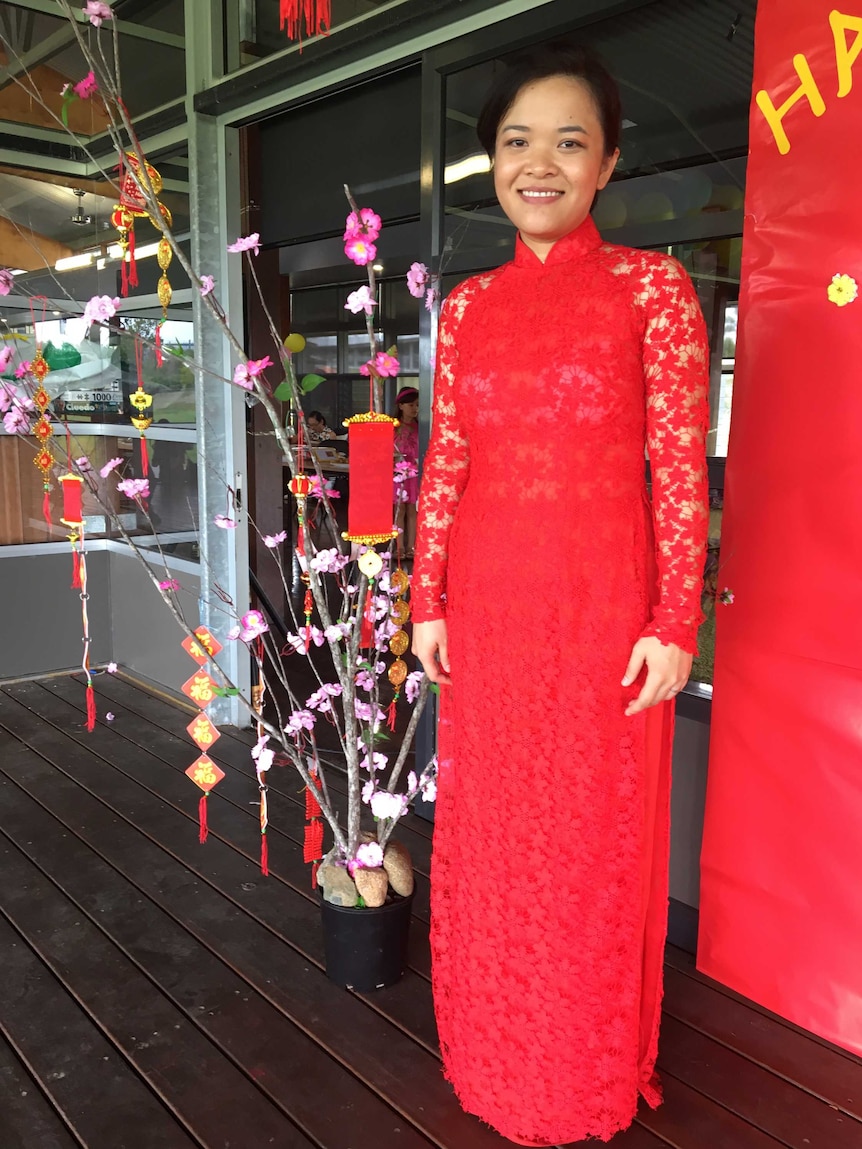 woman in a red dress standing next to some flowers