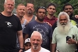 Group of men standing together outdoors all smiling.